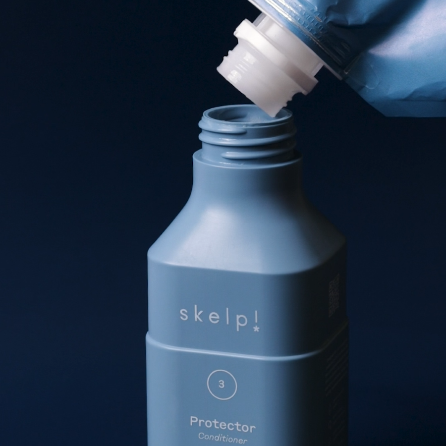 sustainable refill pouch pouring premium conditioner into recycled haircare bottle