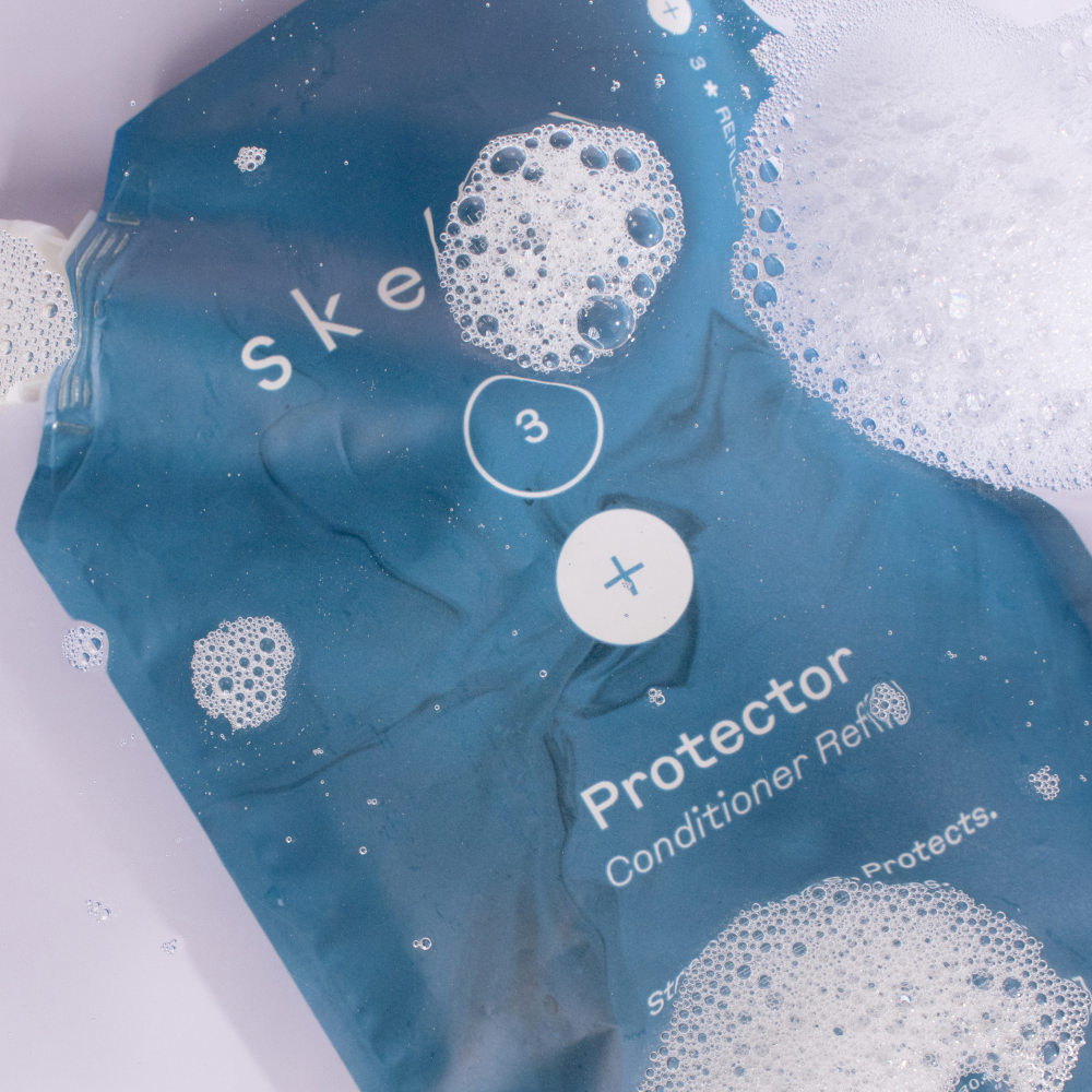 sustainable Australian conditioner refill pouch lying in water with bubbles around it.
