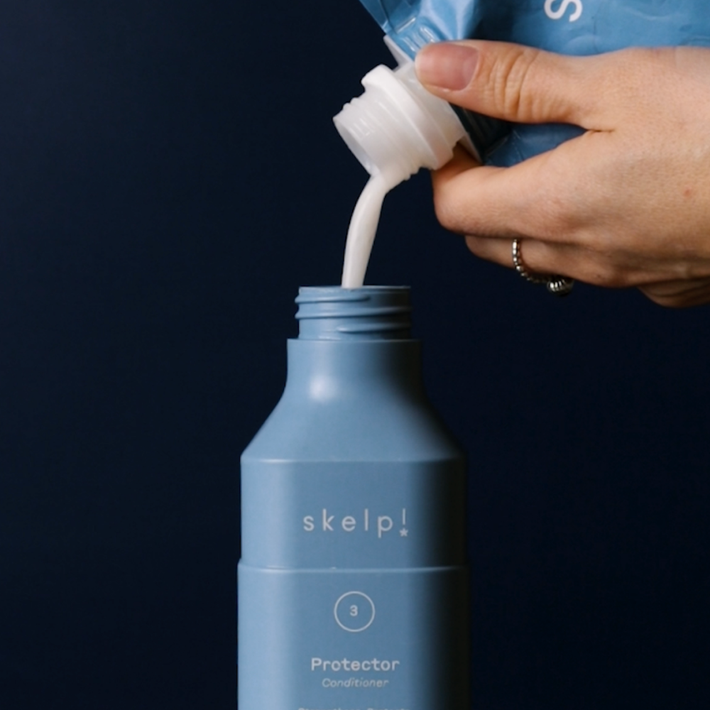 Sustainable skelp refill pouch being poured into recycled shampoo bottle