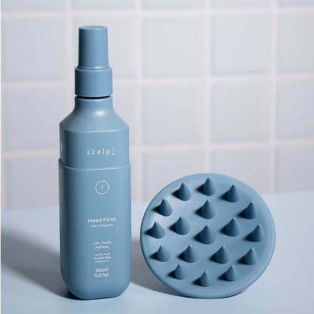 Blue bottle skelp haircare and textured hair brush on a light blue tiled background