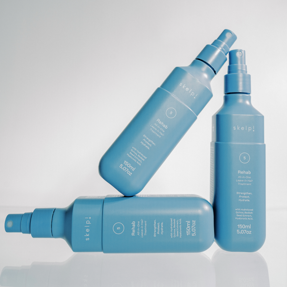 Beautiful hero shot of three skelp! rehab all in one leave in hair treatment bottles.