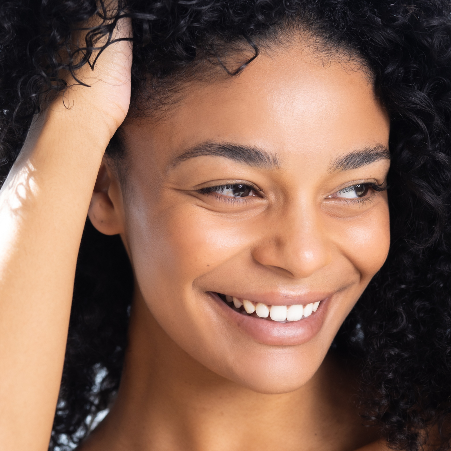 Close-up of a woman with a bright smile and curly hair.