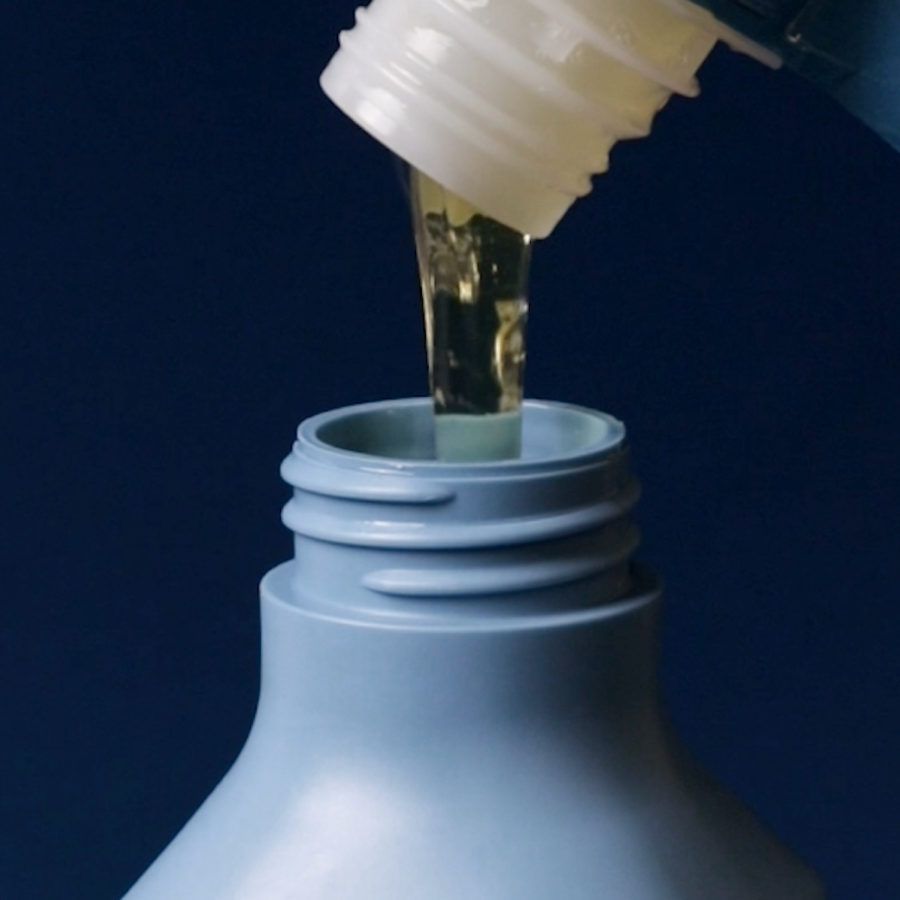 macro shot of sustainable refill pouch pouring premium Australian shampoo into bottle.
