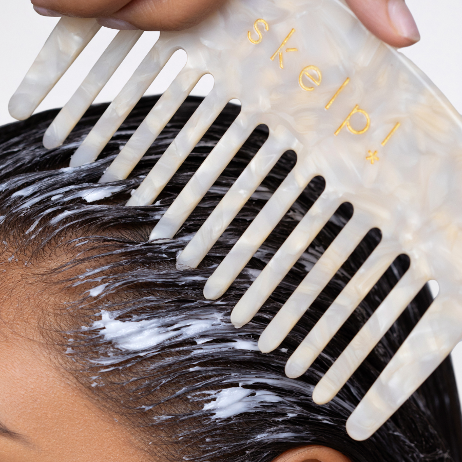 Person using a wide tooth comb with hair mask on hair