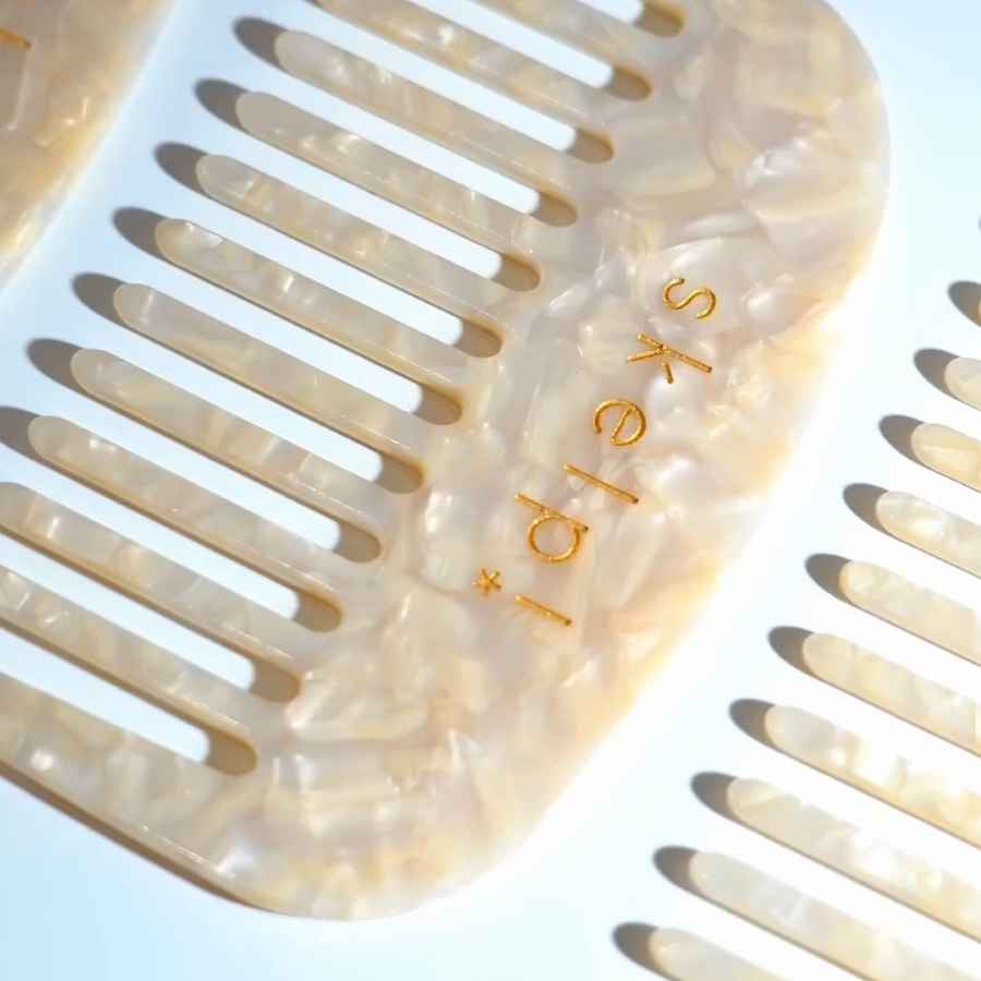 Beige hair comb with 'Skep' branding on a light blue background