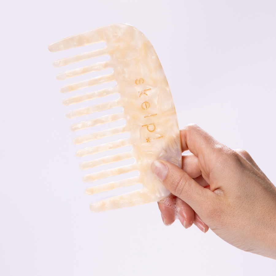 Hand holding skelp! a premium wide tooth comb. Marble texture comb. 
