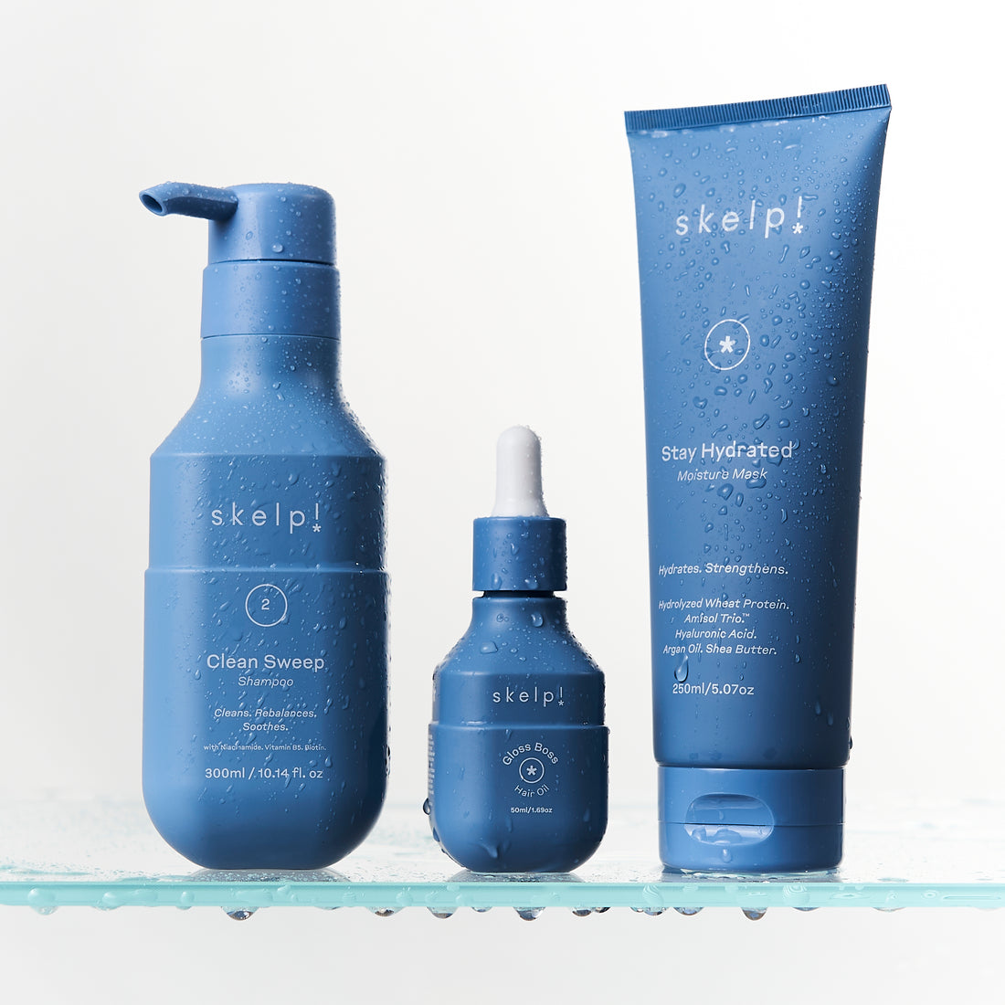 Skelp Clean Sweep Shampoo, Skelp Gloss Boss Hair Oil &amp; Skelp Stay Hydrated Mask pictured on a light gray background.