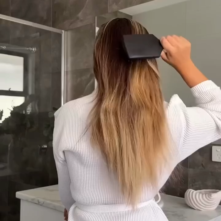 skelp! haircare user brushing their long blonde hair in a bathroom.